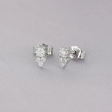 Broqueles Tré Cima de Oro Blanco 14k, en toma de estudio sobre tela lila.