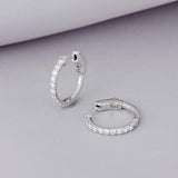 Arracadas Elaine Vault Mediana de Oro Blanco 14k de 0.90 cts, en toma de estudio sobre tela lila.