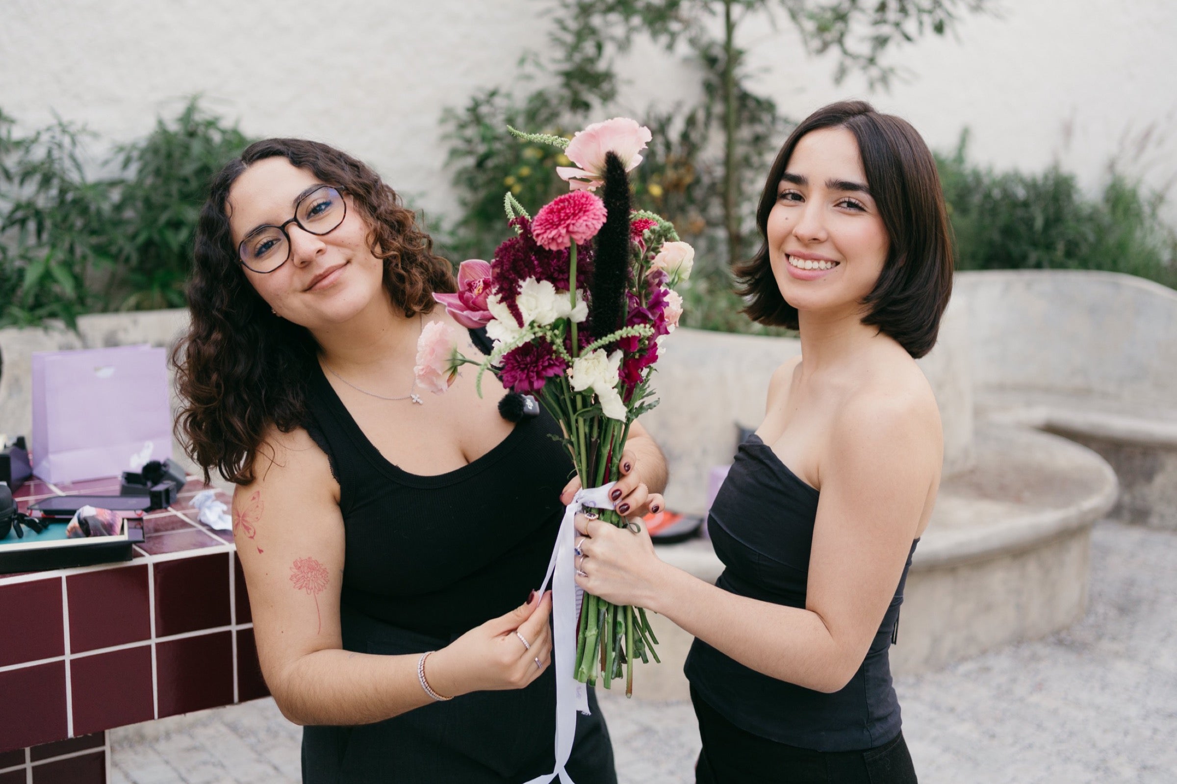 María y Natalia sosteniendo flores durante una producción de Elaine