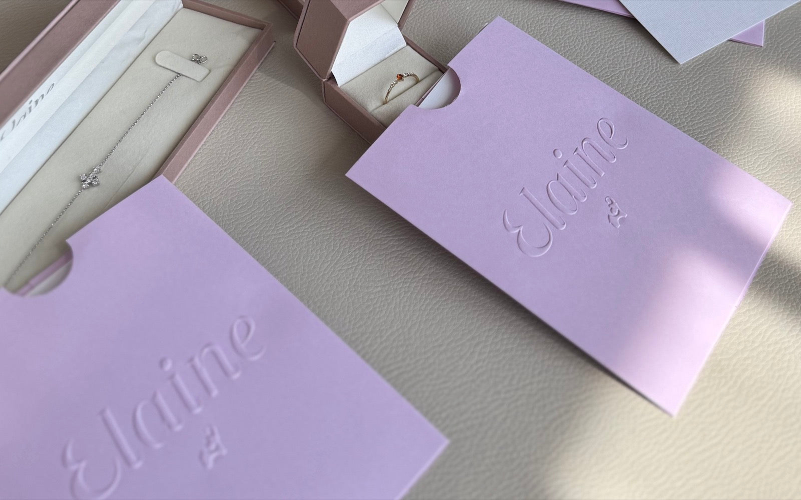 Empaque Elaine: sobres lila con el sello de la casa, estuches con sus piezas y certificados sobre piel clara